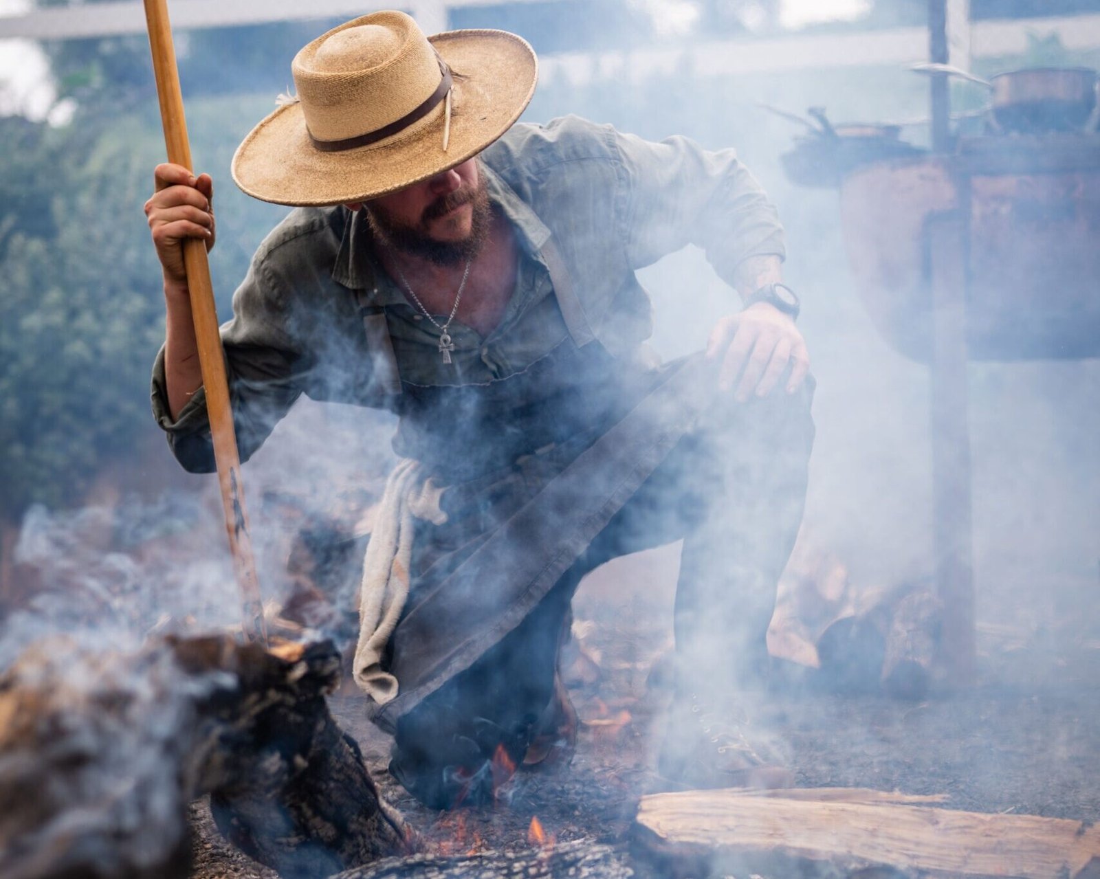 Man with hat cooking over hot coals